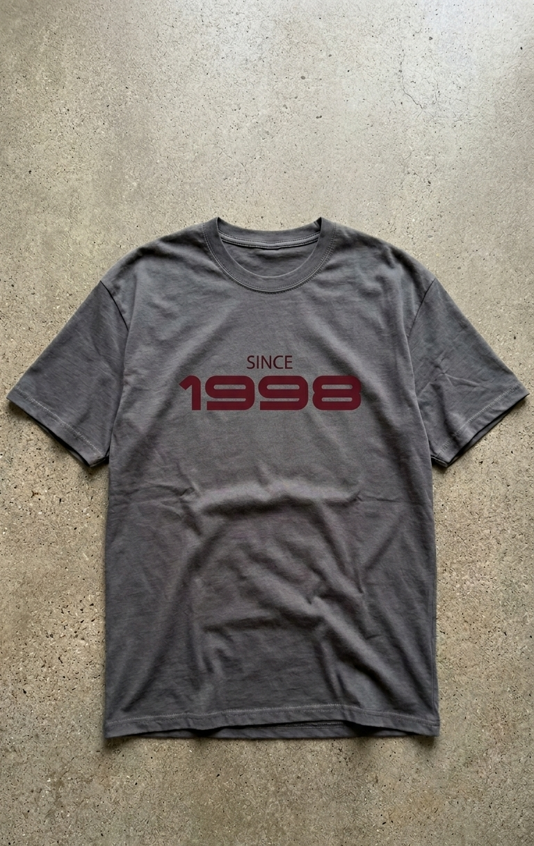 Gray t-shirt with 'Since 1998' text on a concrete surface