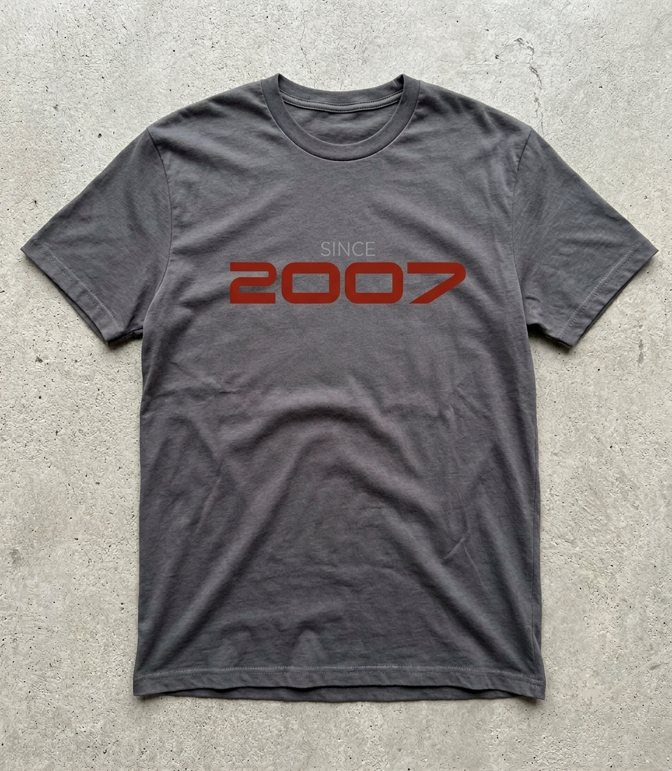 Gray t-shirt with 'Since 2007' text in red on a concrete surface