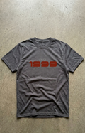Gray t-shirt with 'Since 1999' text in red on a concrete floor.