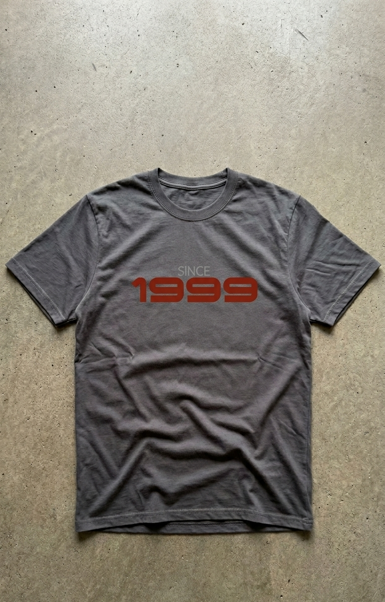 Gray t-shirt with 'Since 1999' text in red on a concrete floor.