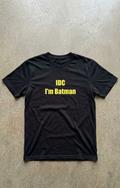 Black t-shirt with yellow text 'IDC I'm Batman' on a concrete floor.