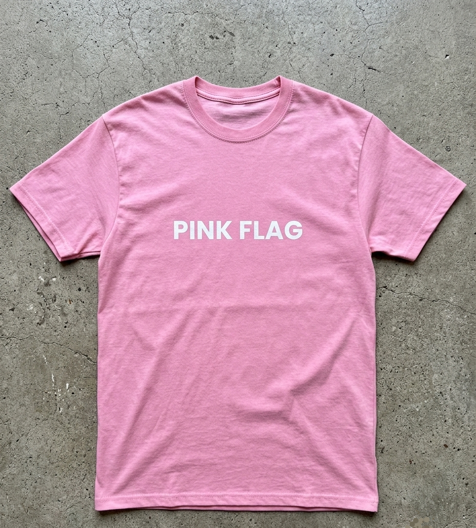 Pink t-shirt with 'PINK FLAG' text on a concrete surface