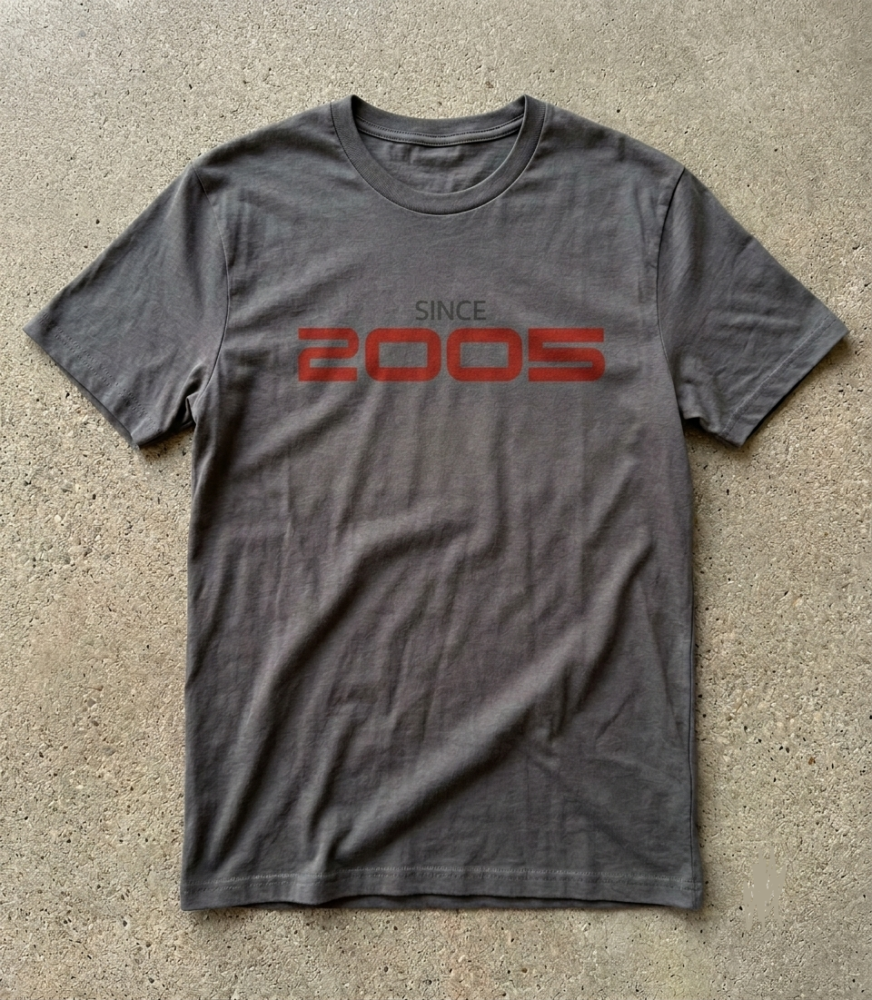 Gray t-shirt with 'SINCE 2005' printed in red on a concrete surface